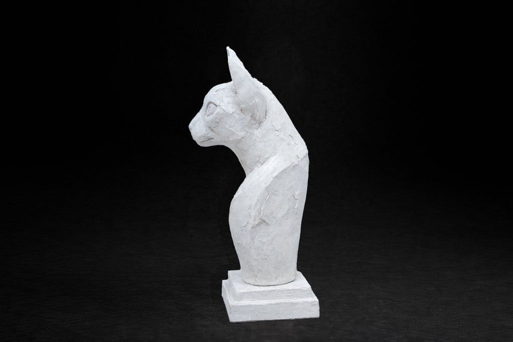 White plaster portrait bust of an Abyssinian cat with large ears on a stepped square base.