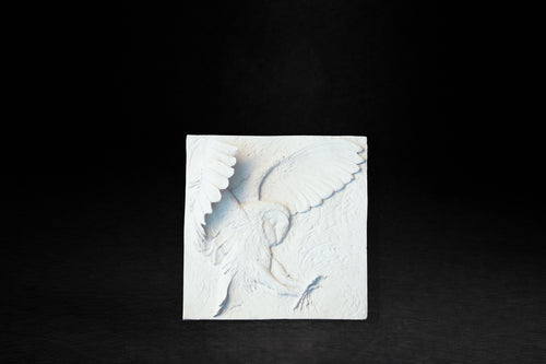 White plaster relief panel depicting a barn owl with wings fully spread in a hunting swoop.