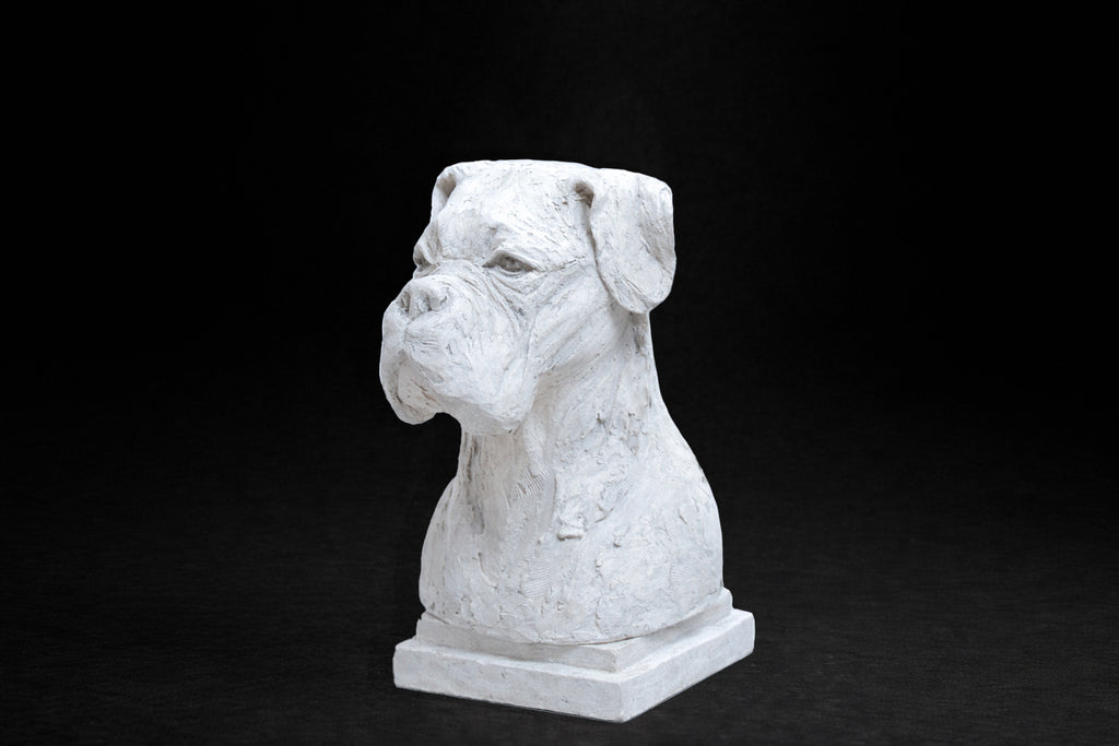 White plaster portrait bust of a Boxer dog with a broad muzzle on a stepped square base.