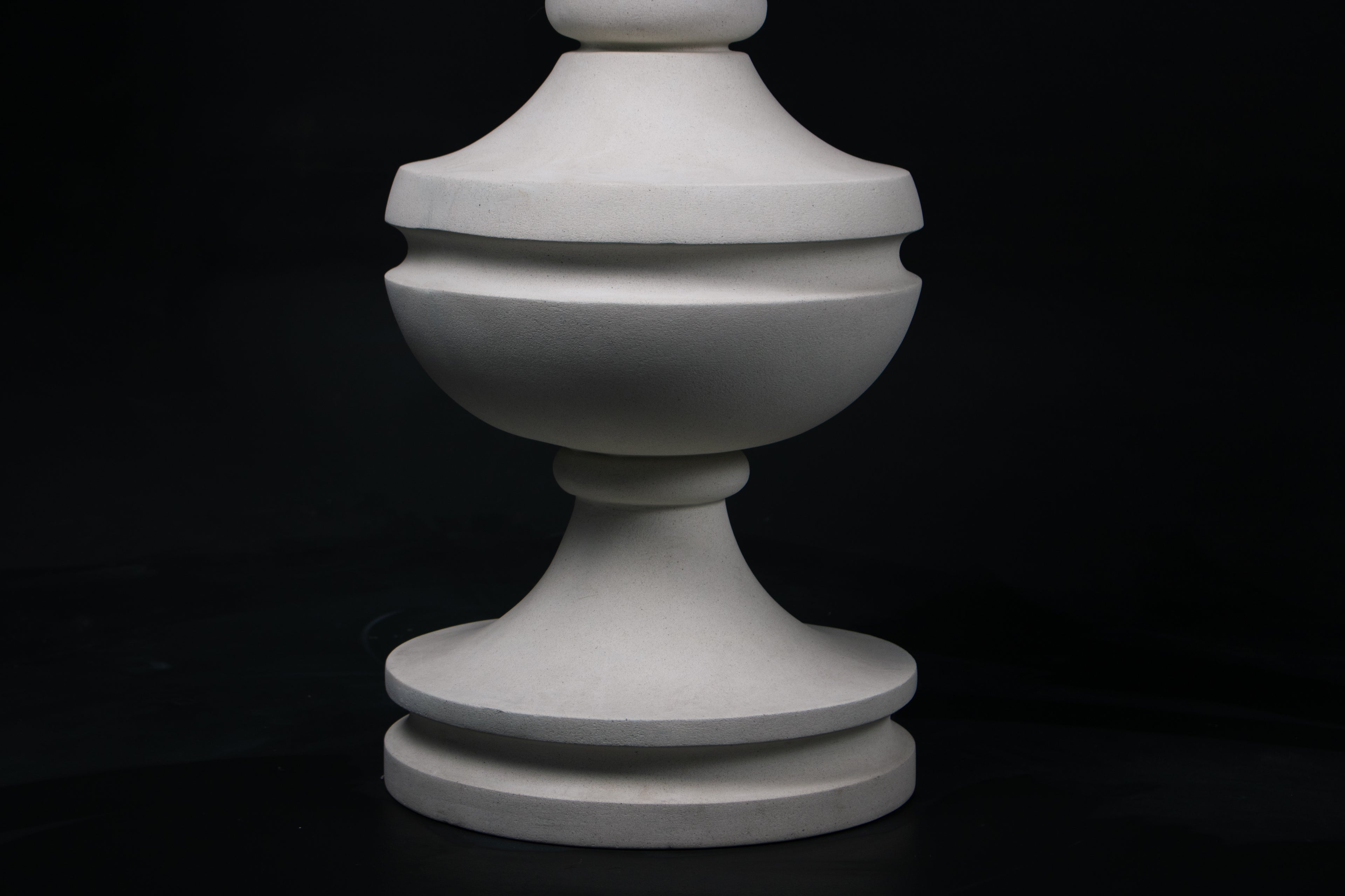 Chalice barstool in white. The substantial turned base draws on classical column and urn forms, a layered circular foot rises through a bulbous lower body, pinches to a narrow waist, then flares outward to support a round white bouclé upholstered seat.