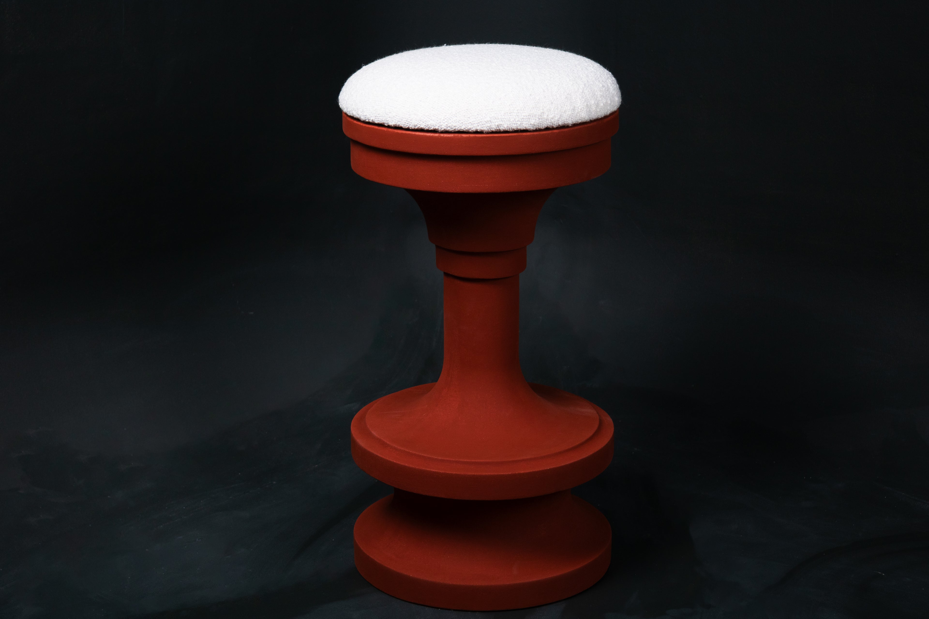 Entasis barstool in terracotta. The pedestal base features layered circular mouldings that taper at the waist, topped with a round white bouclé upholstered seat.