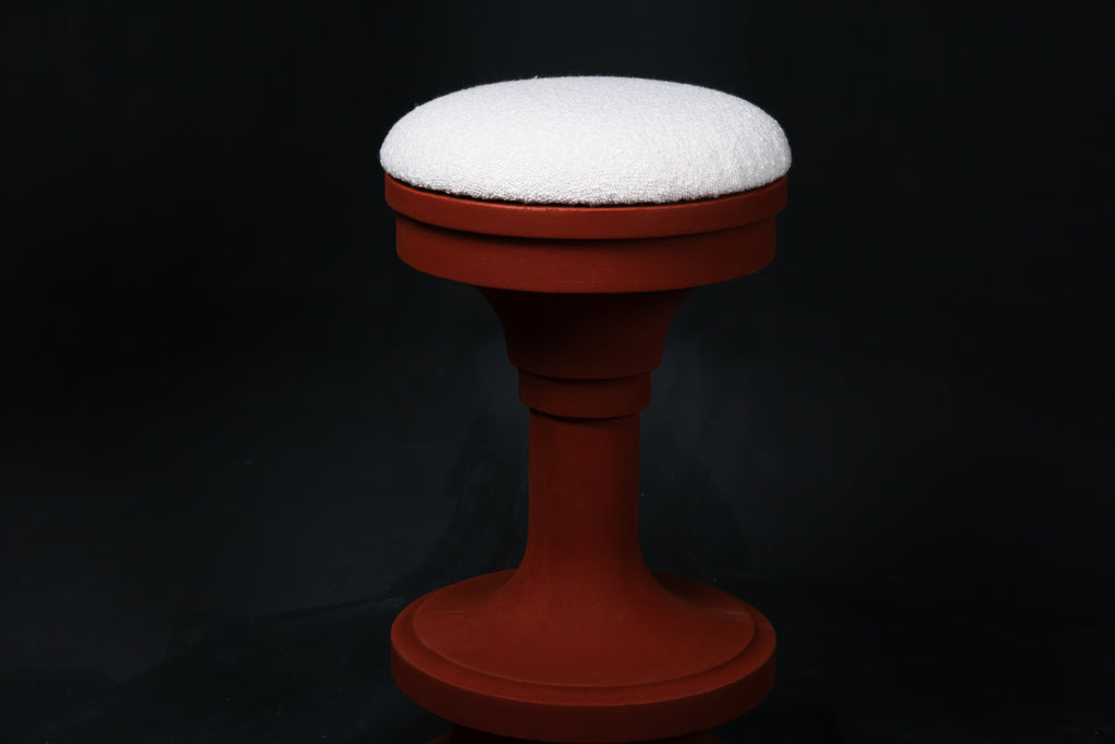 Entasis barstool in terracotta. The pedestal base features layered circular mouldings that taper at the waist, topped with a round white bouclé upholstered seat.