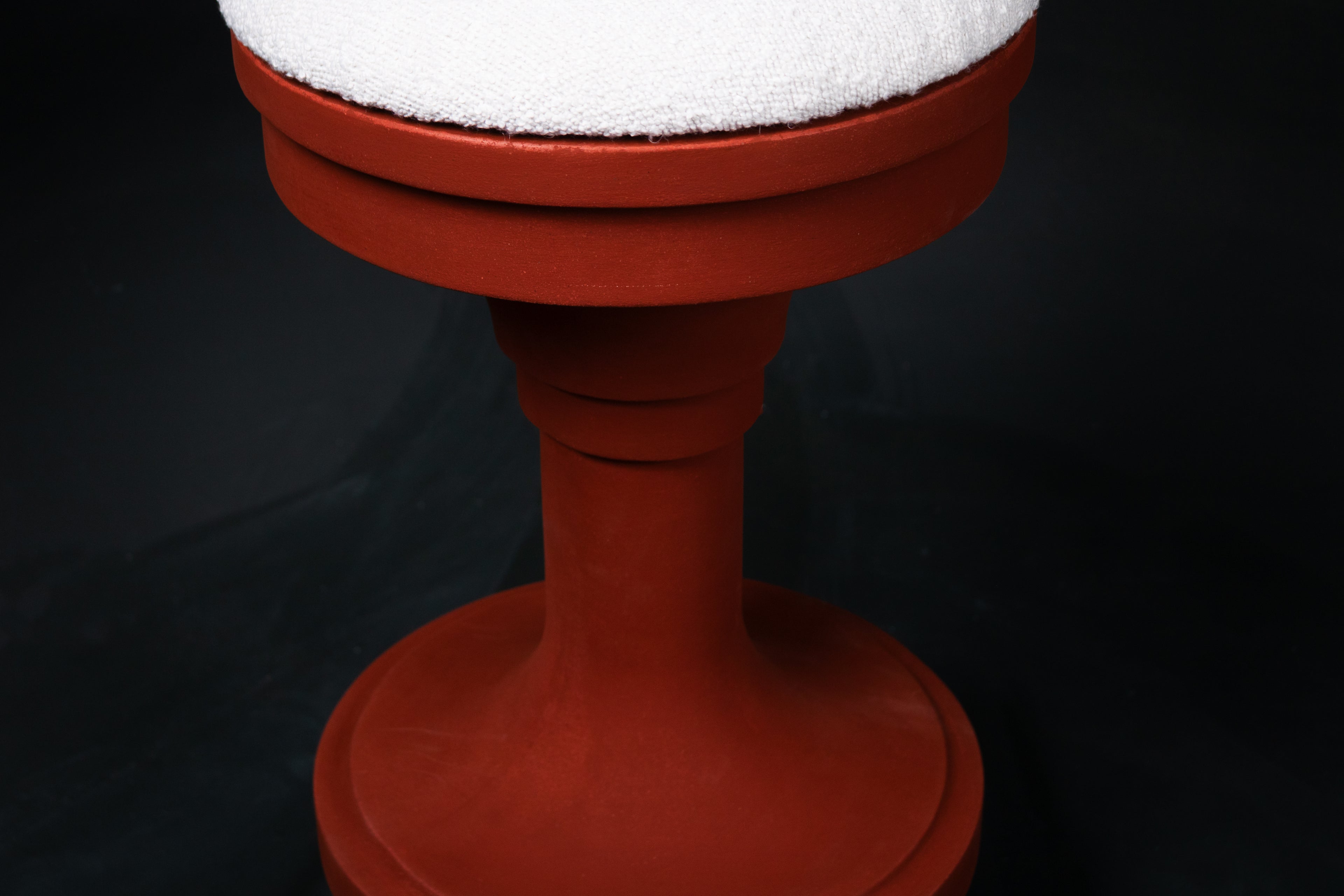Entasis barstool in terracotta. The pedestal base features layered circular mouldings that taper at the waist, topped with a round white bouclé upholstered seat.