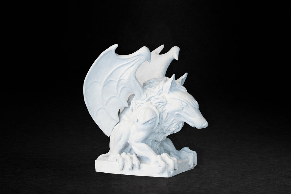 White plaster sculpture of a winged gargoyle in a crouching position on a base