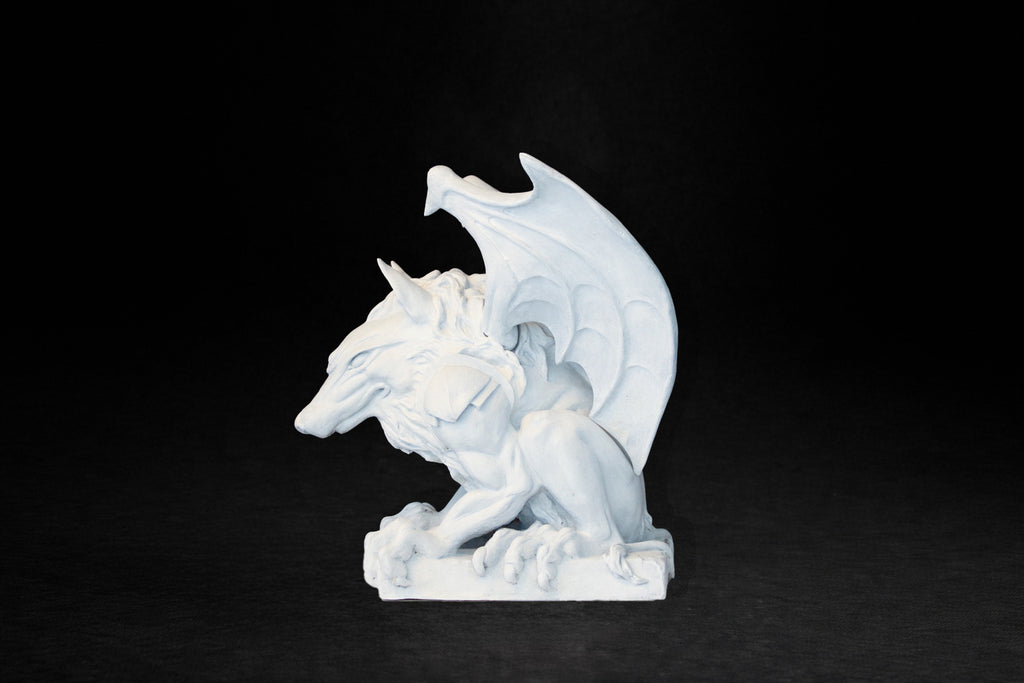 White plaster sculpture of a winged gargoyle in a crouching position on a base
