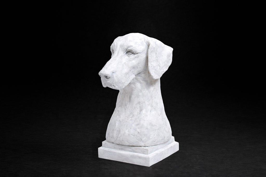 A white plaster bust of a Great Dane by artist Tania Lee. The sculpture is rendered with expressive hand-worked texture. The dog has a calm, dignified expression, long ears falling softly at either side of a broad, finely detailed face.