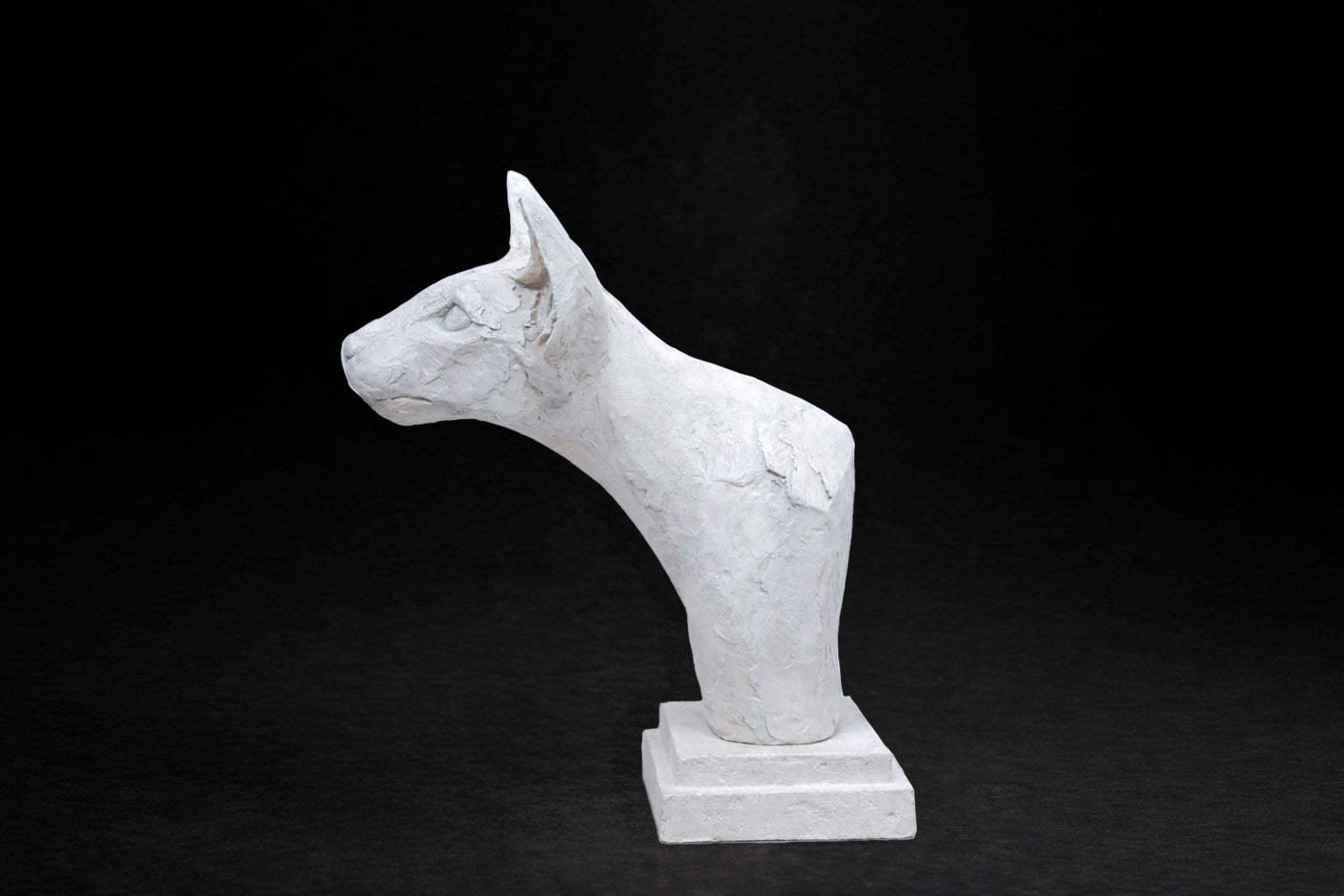 White plaster portrait bust of an Oriental cat with large upright ears and a slender neck on a stepped square base