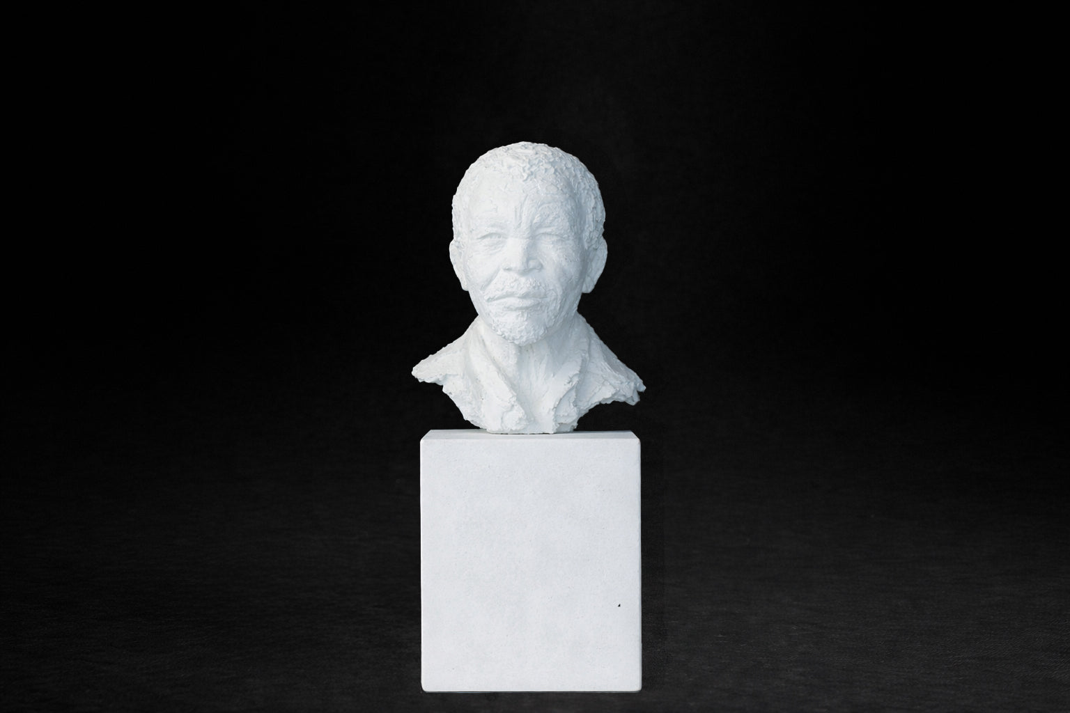 White plaster portrait bust of an elderly man on a square plinth.