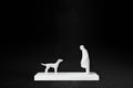 White plaster sculpture of a person and a dog facing each other on a rectangular base.