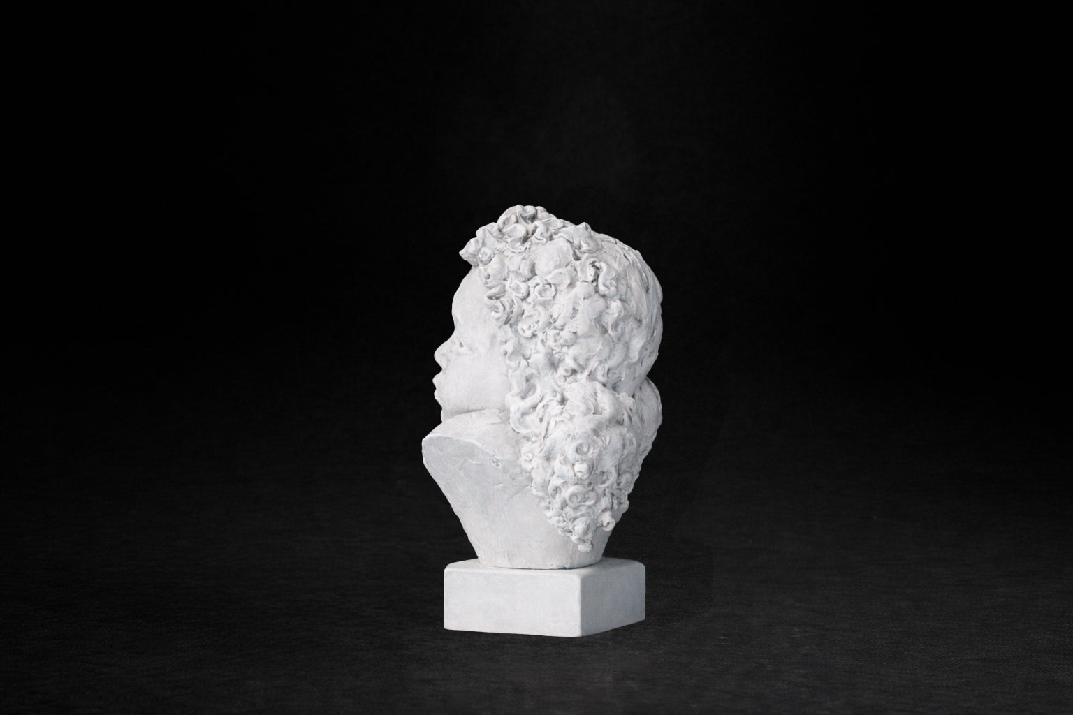 White plaster portrait bust of a young girl with an anguished expression.