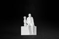 White plaster sculpture of a man sitting on a stone plinth beside his dog, both gazing outward.